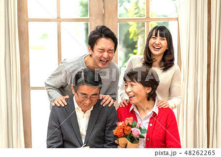 父の日母の日花束プレゼント親孝行な息子娘夫婦笑顔が絶えない家庭仲良し家族の見本の写真素材