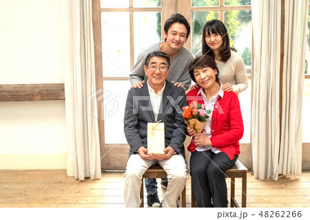 父の日母の日花束プレゼント親孝行な息子娘夫婦笑顔が絶えない家庭仲良し家族の見本の写真素材
