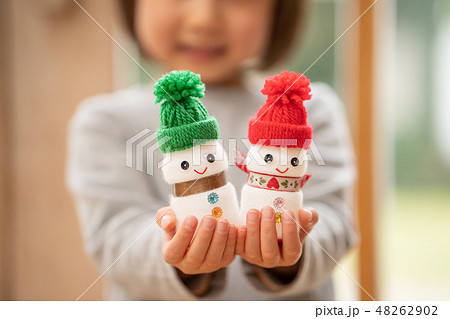 ヤクルトで作ったクリスマス用の雪だるまを見せてくれる可愛い幼稚園の女の子の写真素材