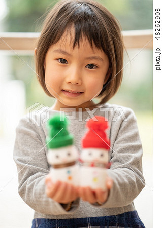 ヤクルトで作ったクリスマス用の雪だるまを見せてくれる可愛い幼稚園の女の子 48262903