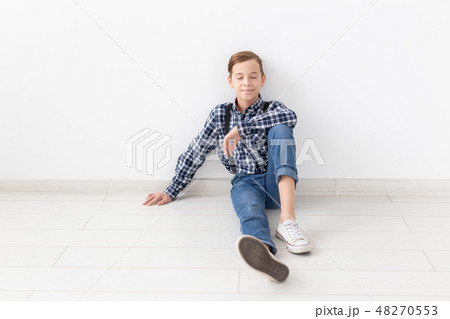 teenager, children and fashion concept - Fashionable boy sitting on floor over white background teenager, children and fashion concept - Fashionable boy sitting on floor over white background 48270553