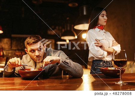 Couple in quarrel, man eats at bar counter Couple in quarrel, man eats at bar counter 48278008
