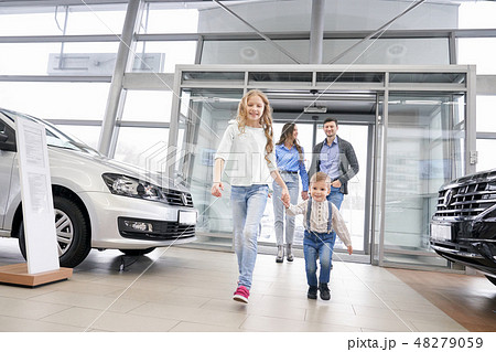 Happy family with children entering dealership showroom. 48279059