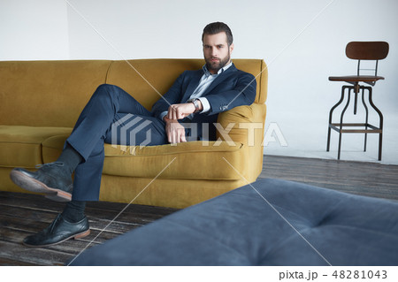 Successful young businessman is sitting on office sofa and looking at camera Successful young businessman is sitting on office sofa and looking at camera 48281043