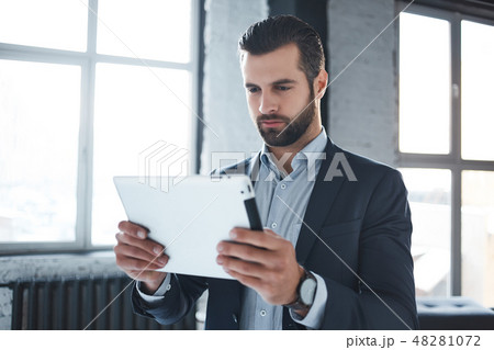 Working day...Serious bearded businessman in stylish suit and with branded watch on his hand is Working day...Serious bearded businessman in stylish suit and with branded watch on his hand is 48281072
