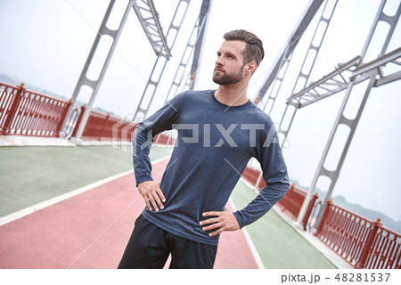 Serious about sport. Handsome young man in sports clothing looking at camera while standing on the Serious about sport. Handsome young man in sports clothing looking at camera while standing on the 48281537