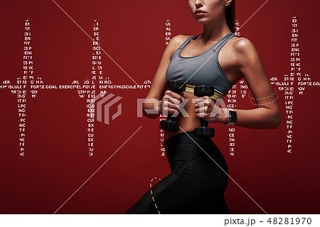 Exercise your mind and body. Sportswoman holds dumbbells standing over red background 48281970