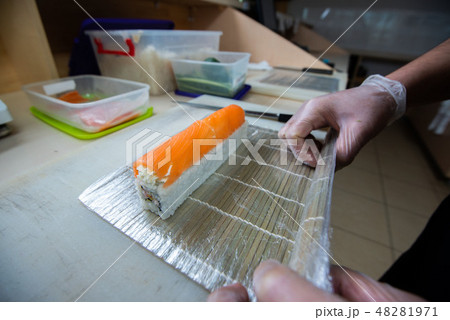 Cook hands making japanese sushi roll. Japanese chef at work preparing delicious sushi roll with eel Cook hands making japanese sushi roll. Japanese chef at work preparing delicious sushi roll with eel 48281971