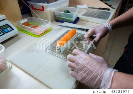 Cook hands making japanese sushi roll. Japanese chef at work preparing delicious sushi roll with eel 48281972