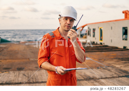 Deck Officer on deck of offshore vessel holds VHF walkie-talkie radio 48283267