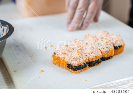 Cook hands making japanese sushi roll. Japanese chef at work preparing delicious sushi roll with eel Cook hands making japanese sushi roll. Japanese chef at work preparing delicious sushi roll with eel 48283504
