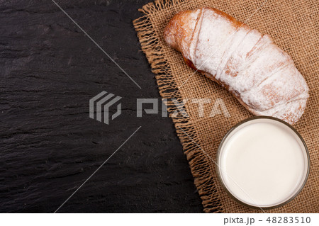 glass of milk with croissants on black stone background with copy space for your text. Top view glass of milk with croissants on black stone background with copy space for your text. Top view 48283510