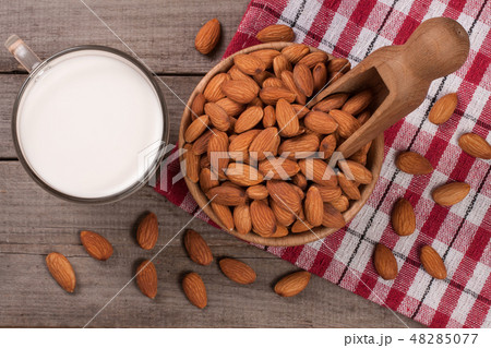 Almond milk in a glass and almonds in a bowl on old wooden background. Top view Almond milk in a glass and almonds in a bowl on old wooden background. Top view 48285077