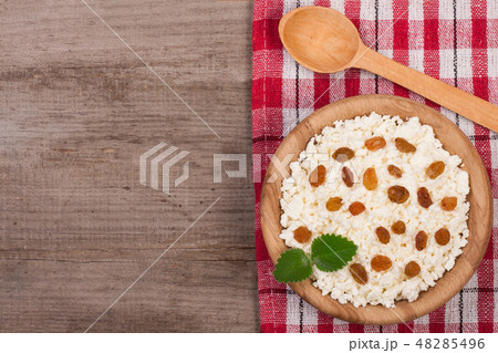Cottage cheese with raisins in a wooden bowl on old wooden background with copy space for your text Cottage cheese with raisins in a wooden bowl on old wooden background with copy space for your text 48285496