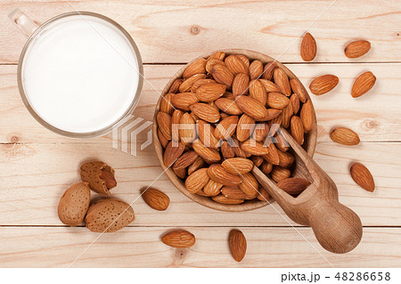 Almond milk in a glass and almonds in a bowl on light wooden background. Top view 48286658