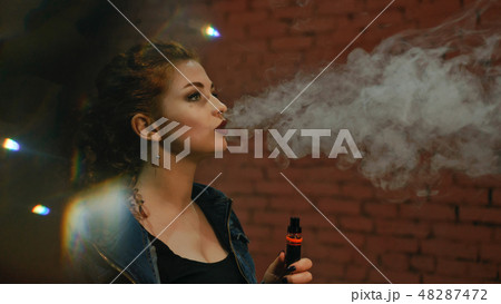 Red-haired girl smokes an electronic cigarette 48287472