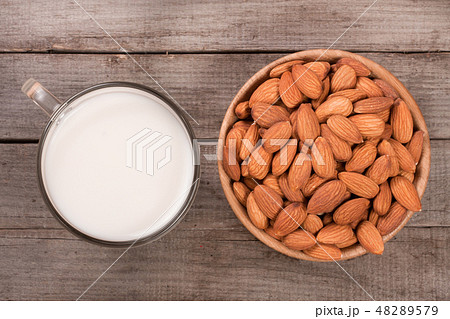 Almond milk in a glass and almonds in a bowl on old wooden background. Top view Almond milk in a glass and almonds in a bowl on old wooden background. Top view 48289579