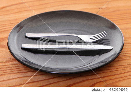 木製テーブルに置かれた黒い皿とカトラリーによる大満足の合図 48290846