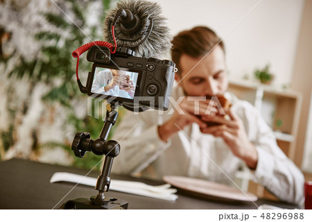 Enjoying food. Close up of digital camera screen with male food blogger eating a sandwich while 48296988