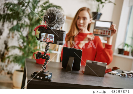 Beauty tips. Young attractive woman showing a makeup palette on camera while recording video review Beauty tips. Young attractive woman showing a makeup palette on camera while recording video review 48297871