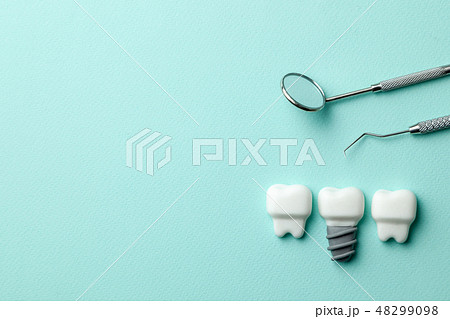 Healthy white teeth and implants  on green mint background and dentist tools mirror, hook. Copy 48299098