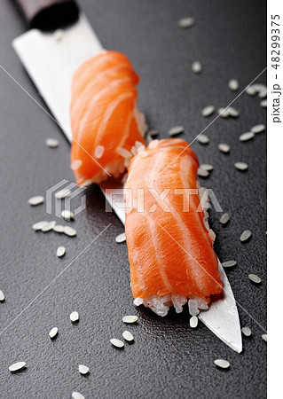 Salmon sushi nigiri on knife over black background Salmon sushi nigiri on knife over black background 48299375