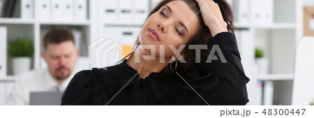 Beautiful smiling brunette woman in office tidying hair 48300447