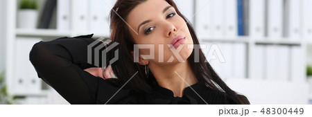 Beautiful smiling brunette woman in office tidying hair 48300449