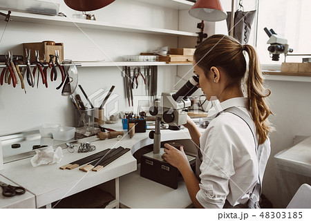 She knows what she is doing. Portrait of female jeweler looking at the new jewelery product through 48303185
