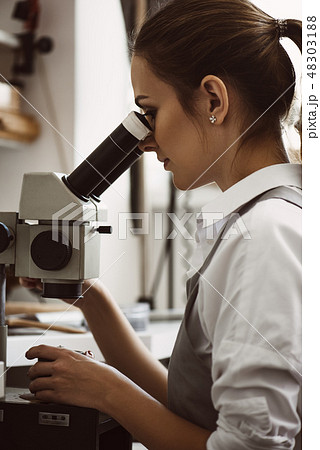 Very close. Vertical portrait of female jeweler looking at the new jewelery product through 48303188