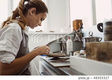 Secret technology. Side view of young female jeweler working on a new silver ring at her workbench Secret technology. Side view of young female jeweler working on a new silver ring at her workbench 48303327