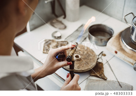 Working with a fire. Female jeweler's hands soldering and welding silver ring at her jewelry making 48303333