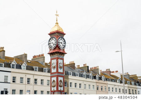 イギリス郊外の街並み クリーム色のカラフルな建物と飾りのついた時計台 の写真素材
