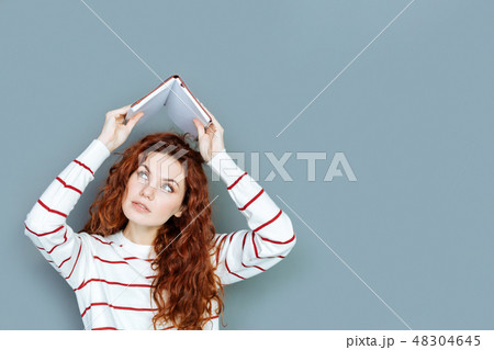 Nice young woman holding a book above her head Nice young woman holding a book above her head 48304645