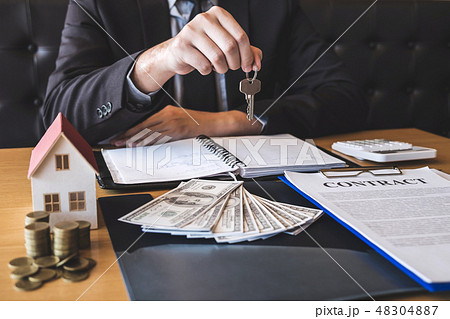 Estate agent giving house keys to client after signing agreement 48304887