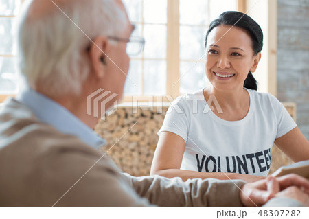 Pleasant volunteer and senior man discussing book 48307282
