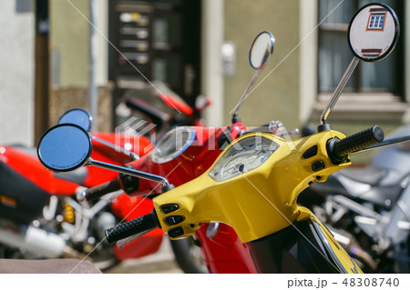 colorful mopeds scooters parked in a row on the street. 48308740