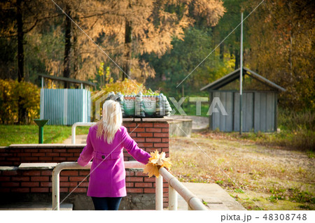 Young blonde woman in violet coat in park 48308748