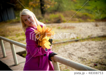 Young blonde woman in violet coat in park 48308753