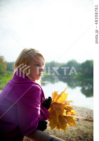 Young blonde woman in violet coat in park 48308761