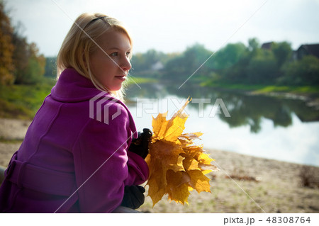Young blonde woman in violet coat in park 48308764