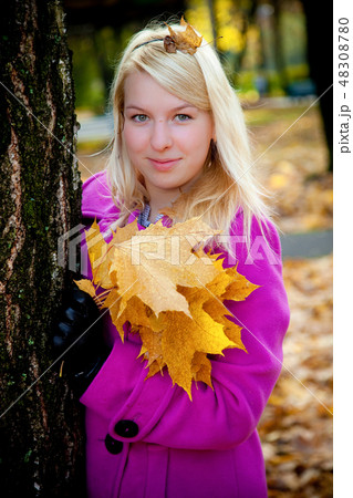 Young blonde woman in violet coat in park 48308780
