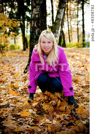 Young blonde woman in violet coat in park Young blonde woman in violet coat in park 48308782