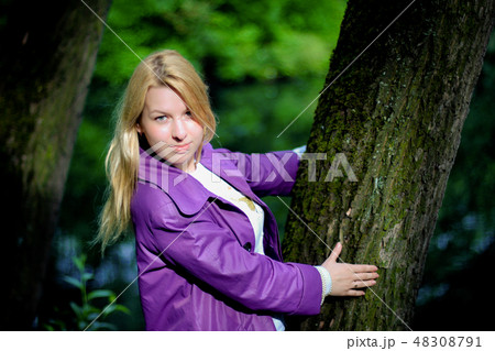 Young blonde woman in violet coat in park Young blonde woman in violet coat in park 48308791