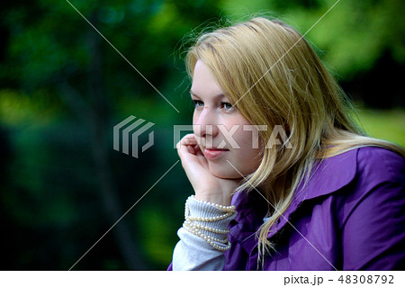 Young blonde woman in violet coat in park 48308792