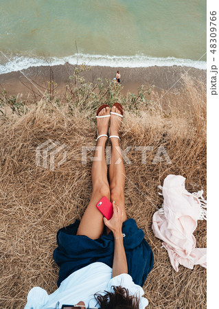 beautiful young girl sitting and holding a smartphone in her hands, top view beautiful young girl sitting and holding a smartphone in her hands, top view 48309766