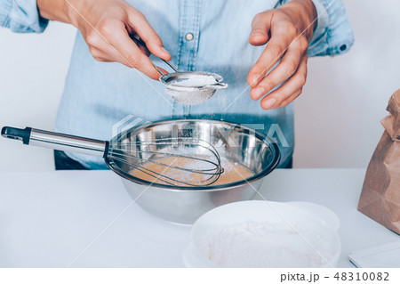 Close-up young woman's hands sift flour 48310082