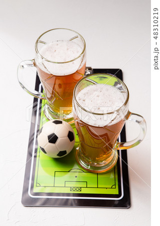 Photo on top of two mugs of frothy beer, table football, ball 48310219