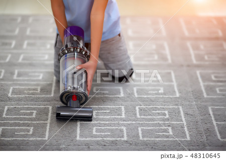 Toddler is cleaning room with vacuum cleaner 48310645
