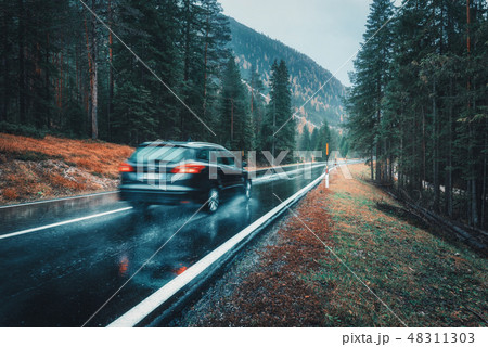 Blurred car in motion on a road in forest in rain 48311303
